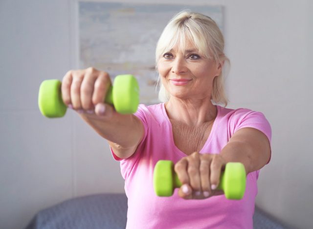 older woman doing chicken wings workout with dumbbells to tone arm flab